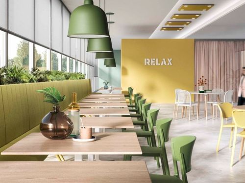 Area relax in un ufficio con sedie colorate e illuminazione con pendenti